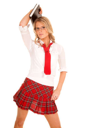 A woman in a school girl skirt holding a book.の写真素材