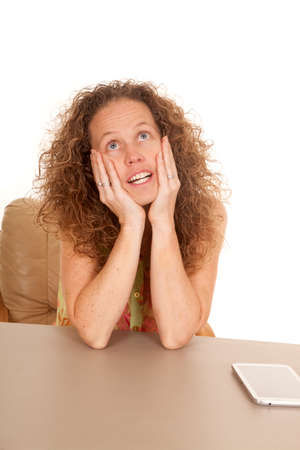 A woman daydreaming instead of working on her tablet.の写真素材