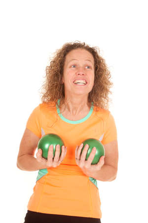 A woman with a smile on her face holding her two green weight balls.の写真素材