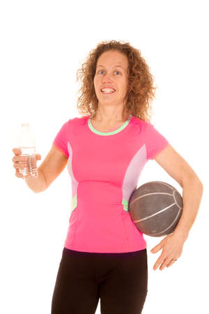 a woman with a smile on her face holding on to a medicine ball and a bottle of water.の写真素材
