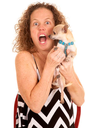 An older woman with a funny expression holding on to her dog.の写真素材