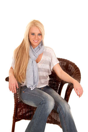 a woman sitting in a chair in her sweater and blue scarfの写真素材