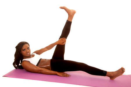 An African American woman laying on her mat with her leg up stretching.の写真素材