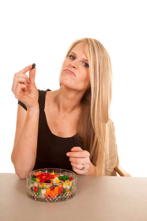 A woman holding up a jelly bean she does not like.の写真素材