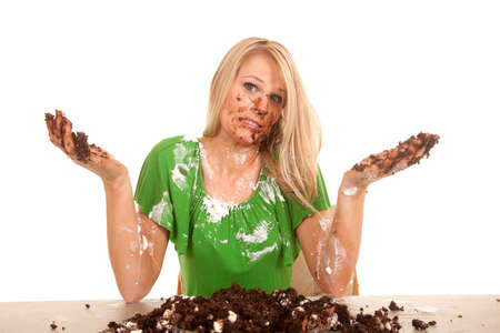 A woman with her hands up and cake all over her face, body and hands.の写真素材