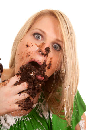 a woman with wide eyes shoving her face with chocolate cake.の写真素材