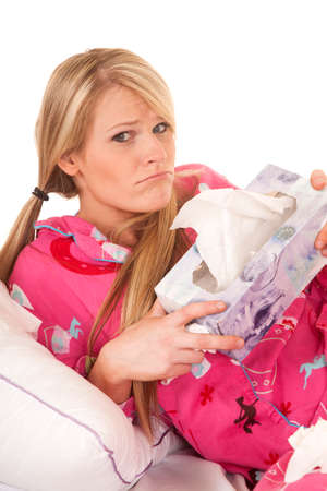 a woman feeling sick, holding on to her tissues with a frown on her face.の写真素材