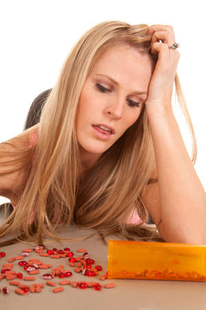 a woman looking down at her pile of pills on the table.の写真素材