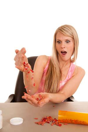 a woman with a shocked expression pouring her pills from one hand to the other.の写真素材