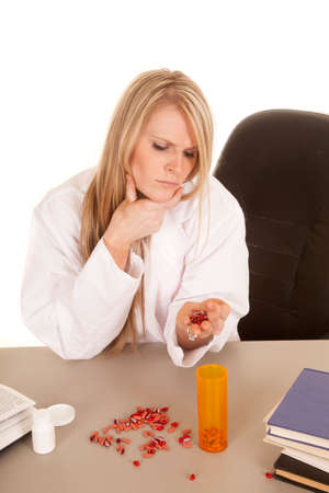 A woman pharmacist looking down at the pills in her hand.の写真素材