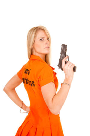 A woman in her prisoner outfit on holding on to a pistol.の写真素材