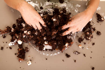 A woman's hands in a cake making a mess.の写真素材