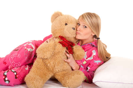 a woman in her pink pajamas holding onto her teddy bear.の写真素材