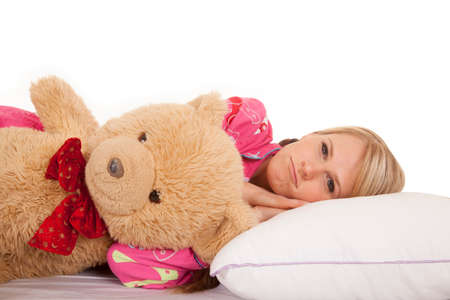 A woman laying on her bed with her teddy bear next to her.の写真素材
