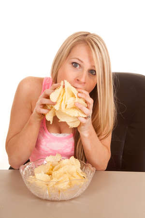 a woman stuffing her face with potato chips.の写真素材