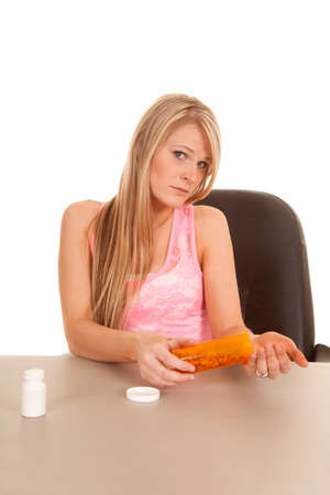 A woman with a bottle full of pills pouring them into her hands.の写真素材