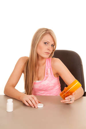 A woman with a bottle of pills in her hand with the lid off.の写真素材