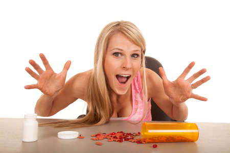 a woman with a bunch of pills on the table with an excited expression on her face.の写真素材