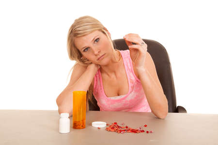a woman with pills laying on a table looking sad.の写真素材