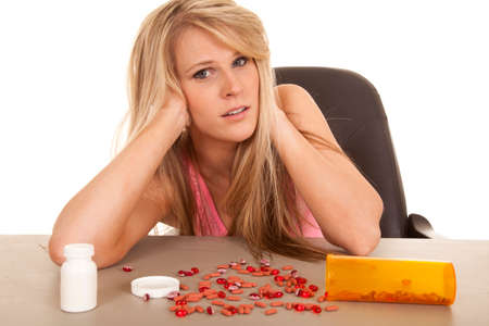 a woman looking stressed with pills on the table.の写真素材