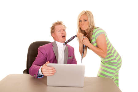 a business man with a shocked expression while his woman co-worker is yanking on his tie in anger.の写真素材