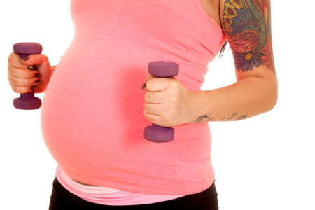 a pregnant woman holding on to her weights by her belly.の写真素材
