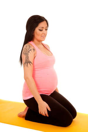 a pregnant woman on a fitness mat kneeling.の写真素材