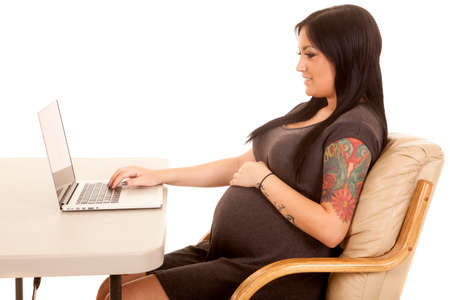 a pregnant woman looking at her laptop with a smile.の写真素材