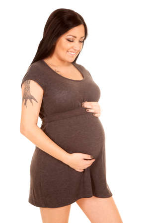 A woman holding on to her pregnant tummy with a smile.の写真素材
