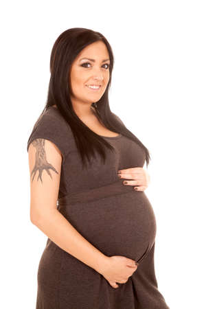 A pregnant woman with a smile holding on to her stomach.の写真素材