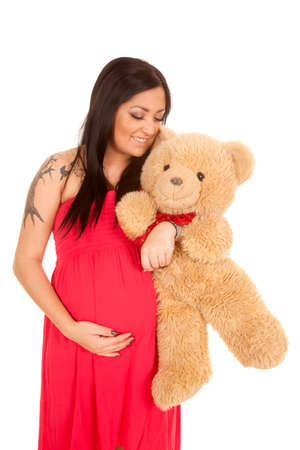 A pregnant woman holding on to a teddy bear.の写真素材