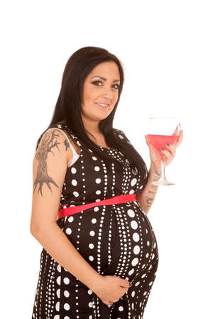 A pregnant woman in her polka dot dress with a smile holding on to her drink.の写真素材