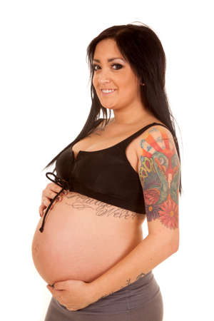 a pregnant woman holding on to her belly with a smile on her face.の写真素材
