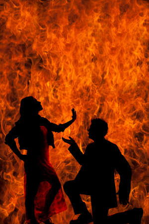 a silhouette of a man and woman with fire behind themの写真素材