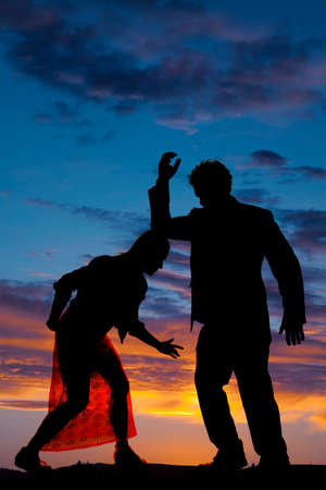 A silhouette of a woman bent over with her man's arm resting on her head.の写真素材