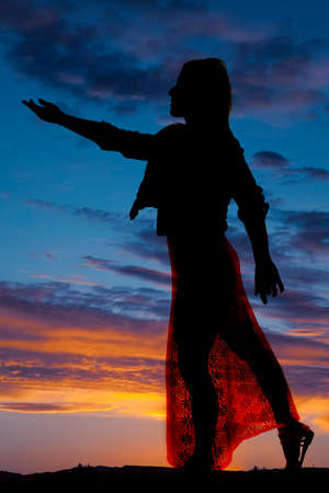 A silhouette of a woman in her dress reaching out.の写真素材