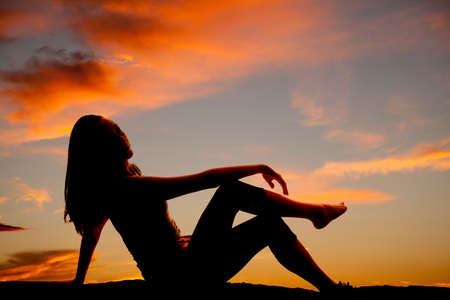 A silhouette of a woman sitting and enjoying the outdoors.の写真素材