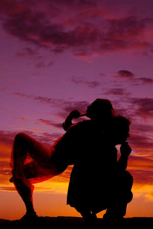 A silhouette of a woman thinking and leaning back on her man's back while he is thinking.の写真素材