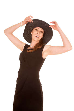 a woman standing with a big smile playing with her hat.の写真素材
