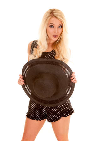 A woman with a playful expression on her face holdig on to her hat.の写真素材