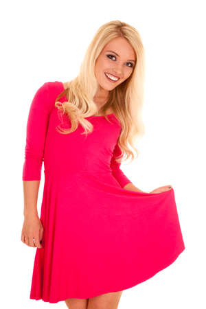 A woman in her pink dress with a smile on her face holding out her dress.の写真素材