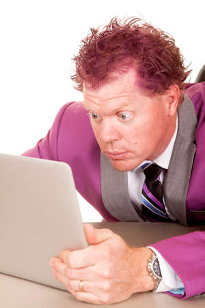a man in his purple suit with big eyes looking at his laptop.の写真素材