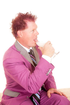 A man sitting and using his tongue to drink out of his glass.の写真素材