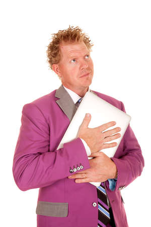 A man with a smug expression holding on to his laptop with a smileの写真素材