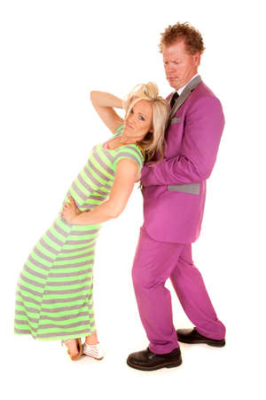 a woman leaning back into the man in the purple suit playing with her hair.の写真素材