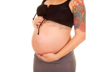 A close up of a woman who is pregnant showing her tattoos.の写真素材