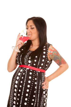 A pregnant woman in her polka dot dress drinking a glass of juice.の写真素材