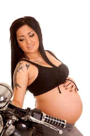 A pregnant woman sitting on a motorcycle with a tattoo on her armの写真素材