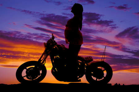 a silhouette of a woman on her motorcycle in the outdoors.の写真素材