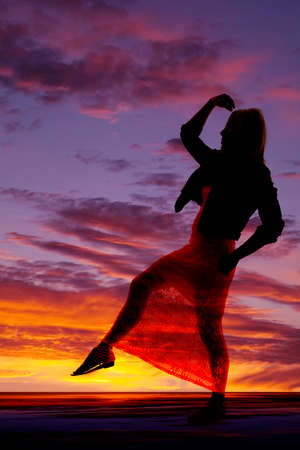 A silhouette of a woman in her lacy dress with her leg up.の写真素材
